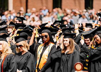 Graduates celebrate on the lawn at commencement