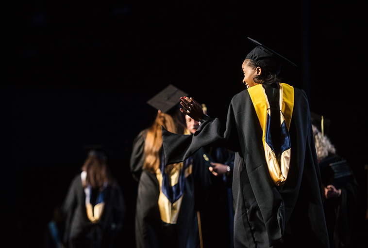 graduates walk across stage