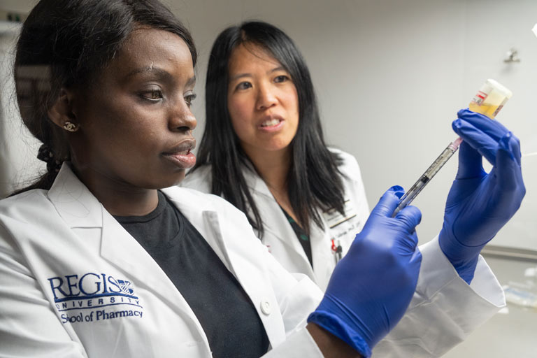 pharmacy student extracting fluid from a vial with a syringe.