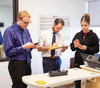 Regis students in different healthcare programs work together in to update medical records at the simulation lab