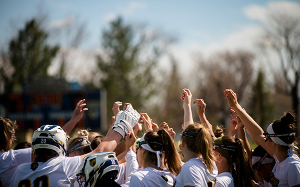 women's lacrosse team huddles on the field