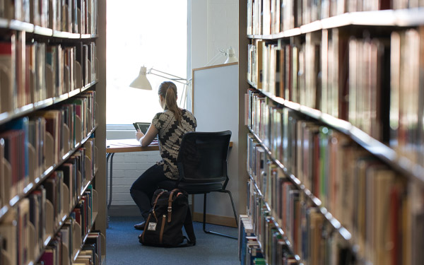 girl studying by books in library