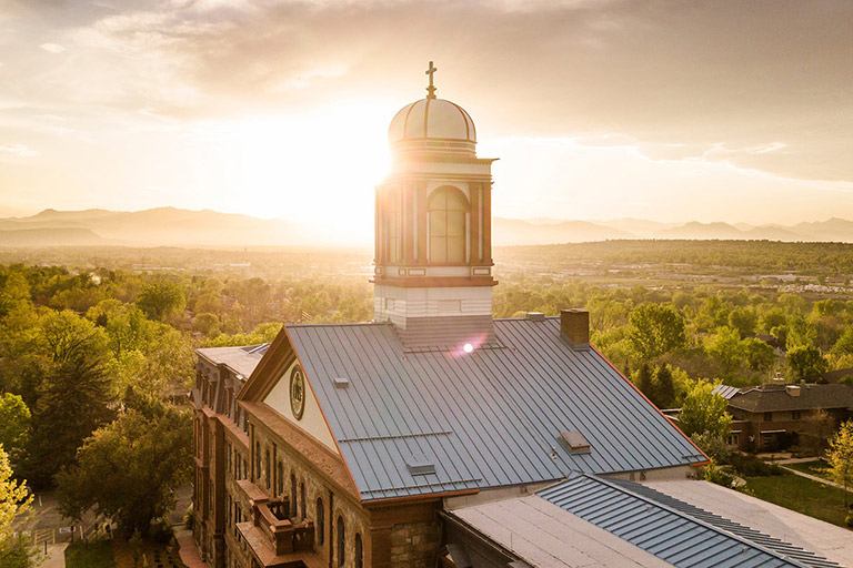 The cupola of historic main hall with the sun rising over the mountains in the background