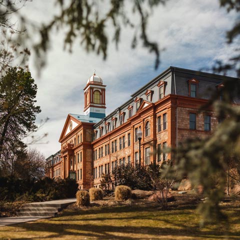 Main Hall at Regis University, a campus building with a central tower and surrounding greenery