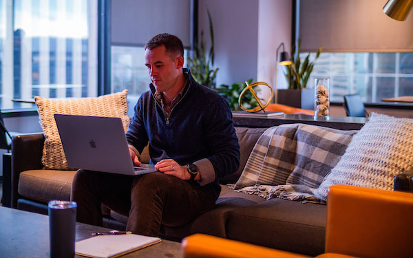 professional man sits on a sofa and works on a laptop