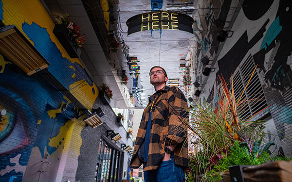 man stands in hallway covered in colorful murals