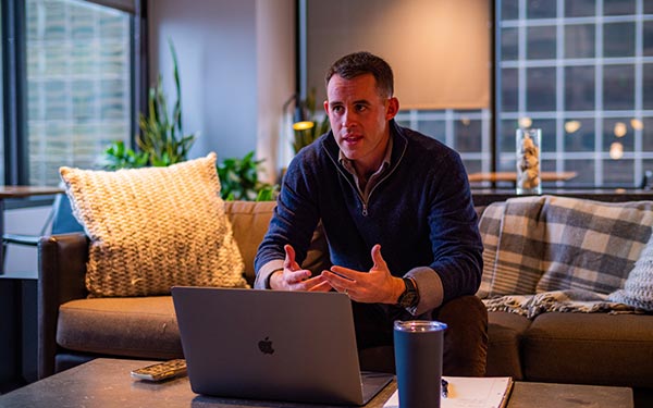 man seated on sofa looks at a laptop screen