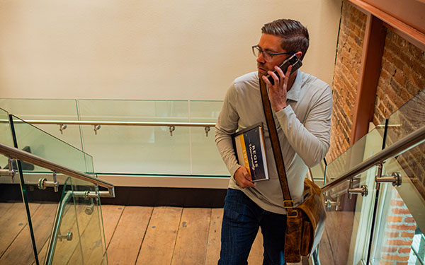 young professional man uses a phone while climbing stairs