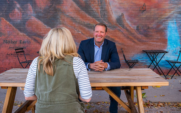 professional man and woman converse while sitting at an outdoor table