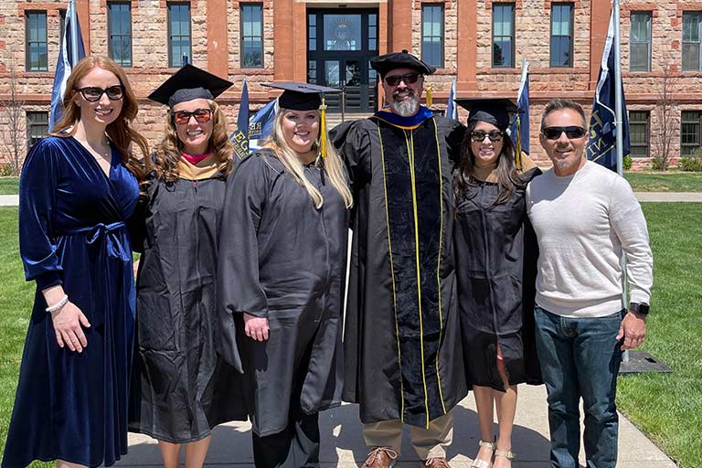 Ken Sagendorf and graduates pose for a picture in full regalia at commenement