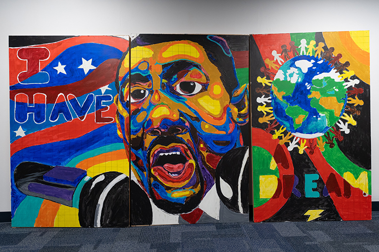 Regis student mural of Dr. Martin Luther King, Jr. that reads "I have a dream" beside a globe encircled by people of all colors 