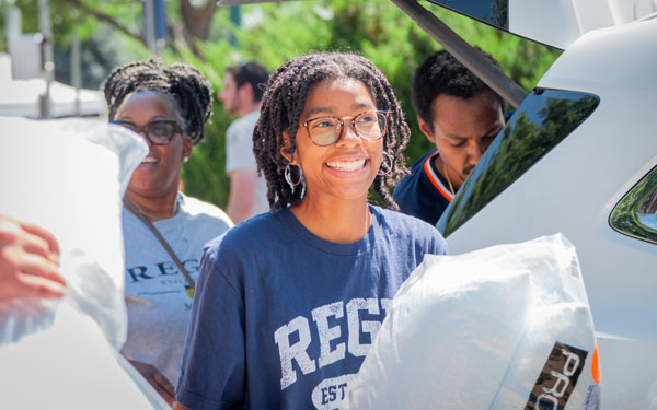 Student smiles as they unload their car on move-in day