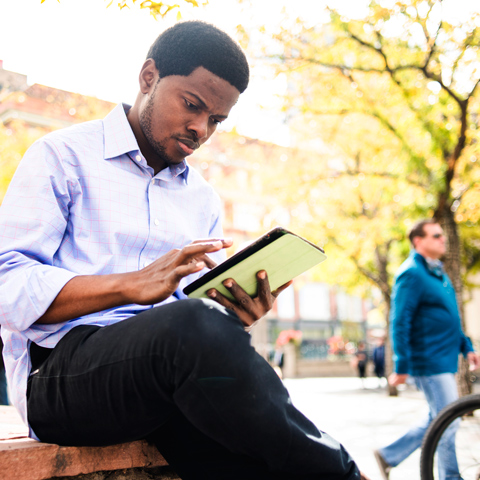 Doctoral student reading on a tablet outside