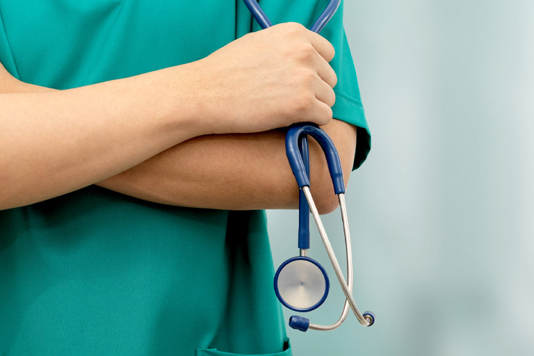 nurse in scrubs holds stethoscope
