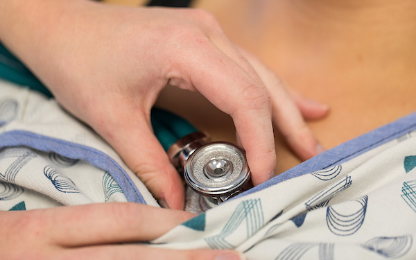 nurse holds a stethoscope to a patient's skin