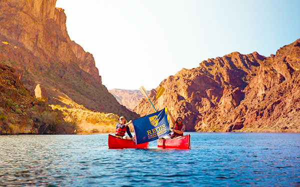 Kayaking students hold Regis flag