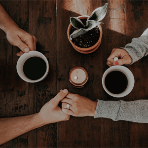 people hold hands on table with coffee