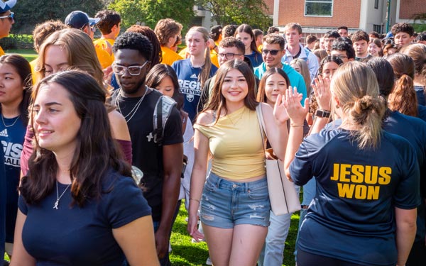 Regis University students walking together and greeting each other on campus.