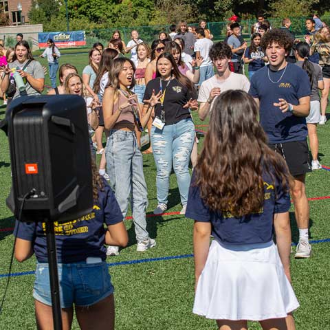 Large group of students dancing and celebrating together during a lively admitted students campus event.