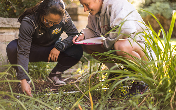 two students taking data outdoors