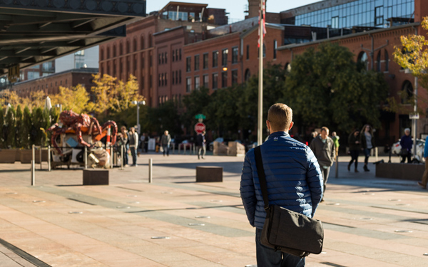 A student walks through a sunlit plaza in downtown Denver