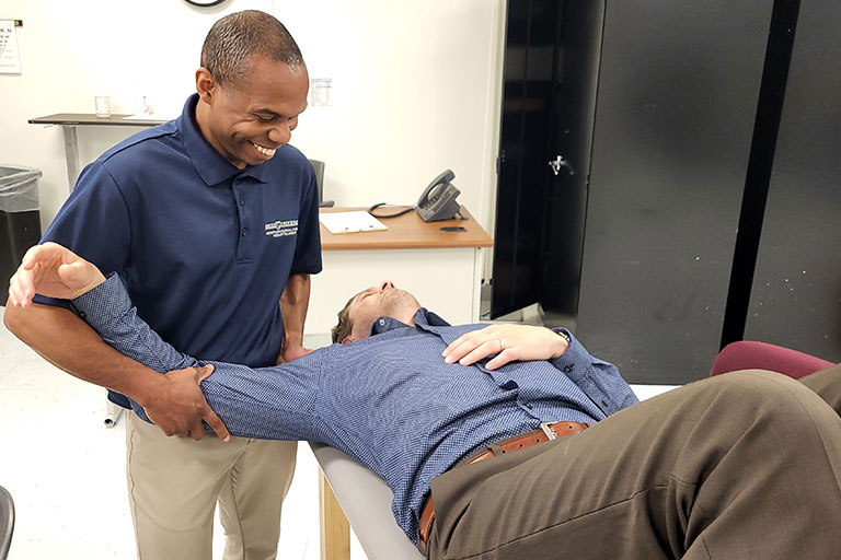 a physical therapist rotates the arm of a patient reclined on a table