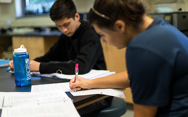 students in classroom laugh with faculty