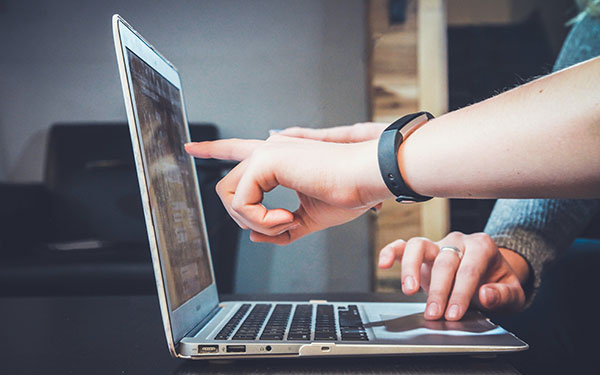 hands pointing at text blocks on computer screen