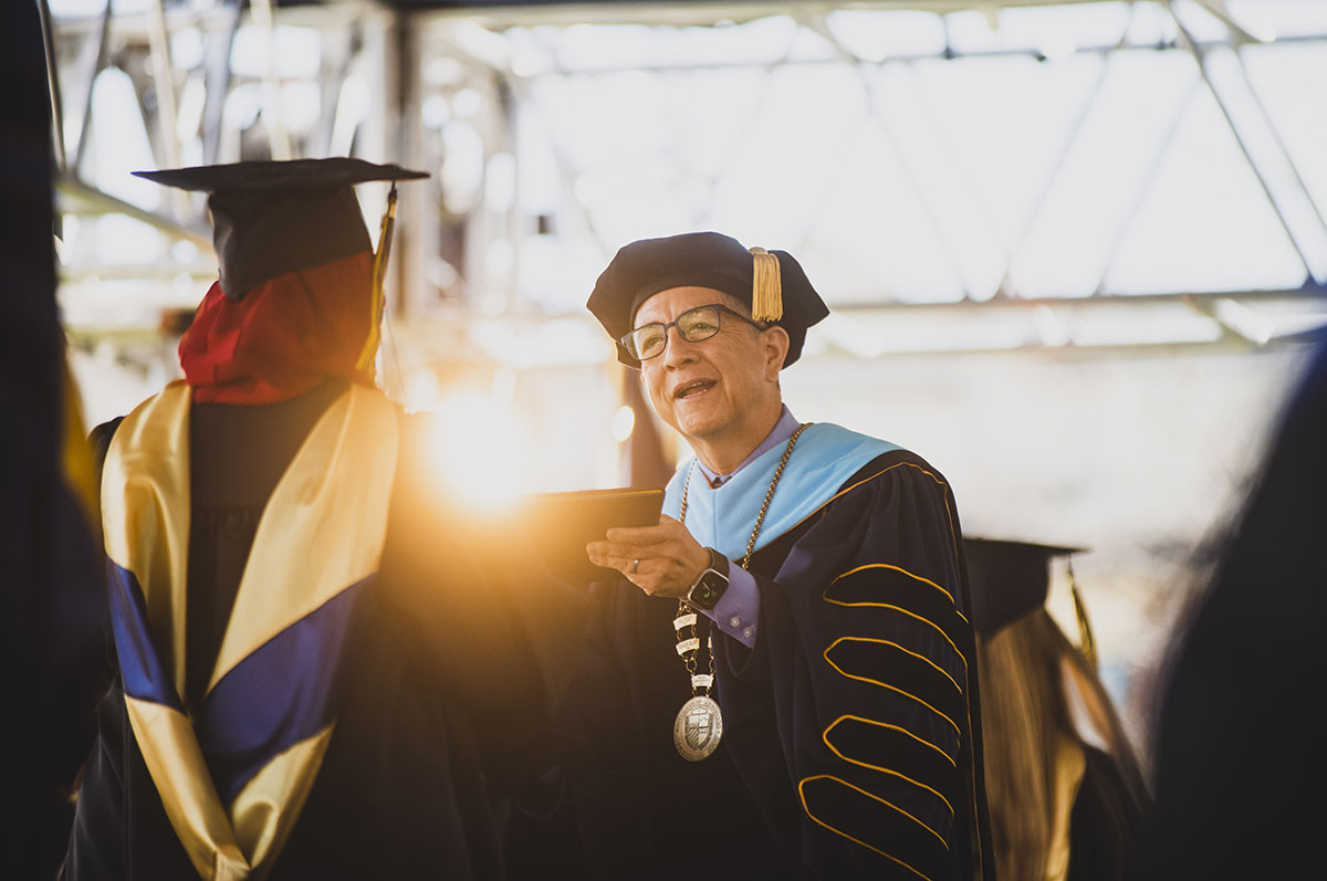 President Salvador Aceves hands a graduate their diploma on the stage at commencement on the Northwest Denver campus