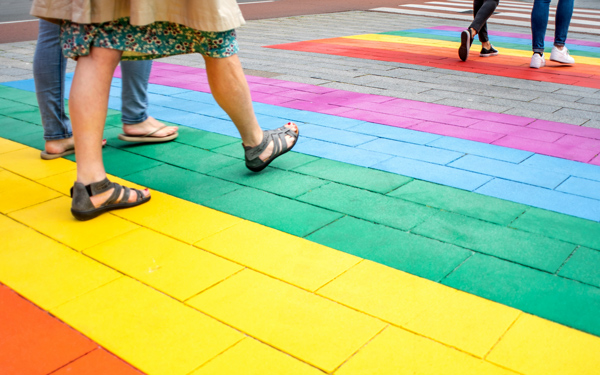 People walking on a rainbow-colored crosswalk symbolizing LGBTQ+ pride 