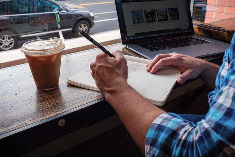 man and woman in professional attire work on a laptop and converse