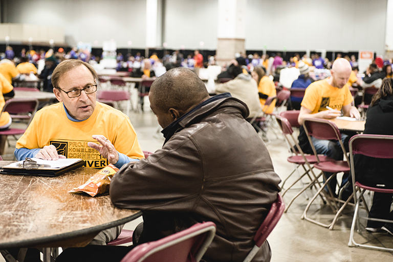 Staff member talking with homeless person at Homeless Connect event