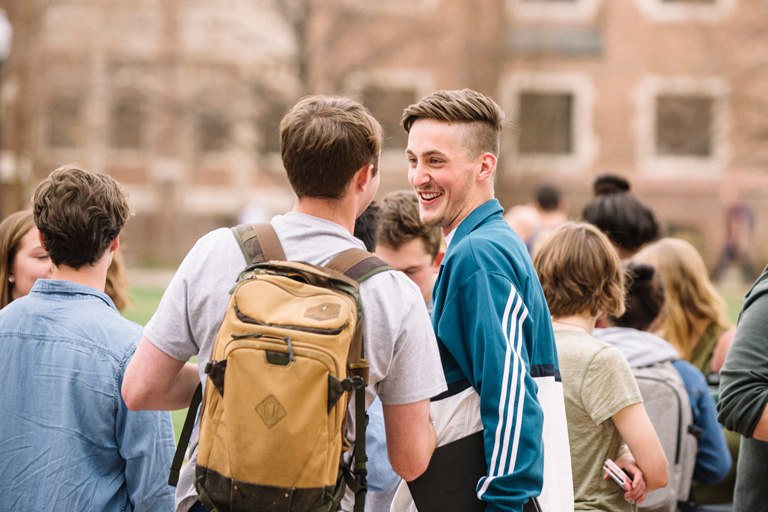 Students standing and talking together on a campus lawn