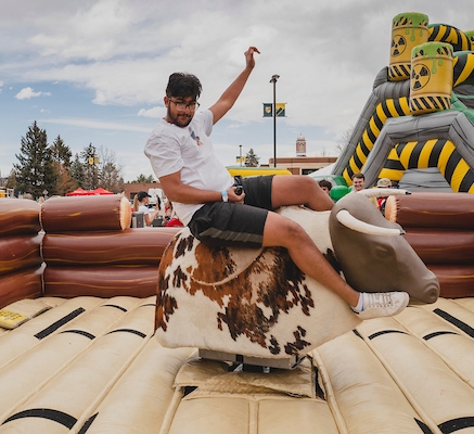 Student riding a mechanical bull during Ranger Week festivities.