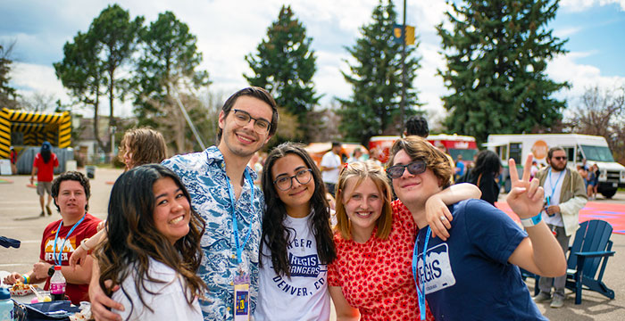 a group of friends poses in front of food trucks and games on Ranger Day