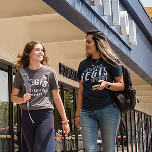 students walk by bookstore at regis square
