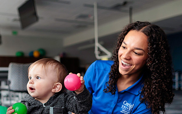 an occupational therapy student works with a toddler and mom in the occupational therapy lab