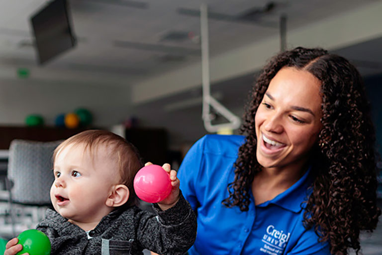 an occupational therapy student works with a toddler in the occupational therapy lab