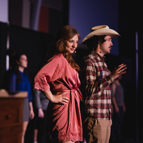 Regis students on stage acting out a play