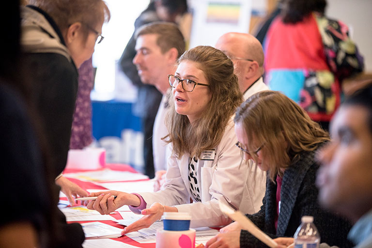 Providers and patients talk over a table at a health fair