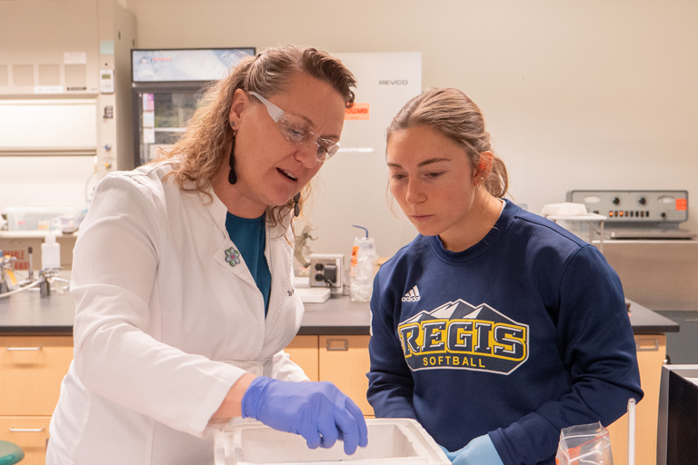 Regis University instructor guiding a student during a hands-on lab exercise