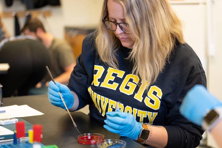 student in a lab conducts an experiment with petri dishes