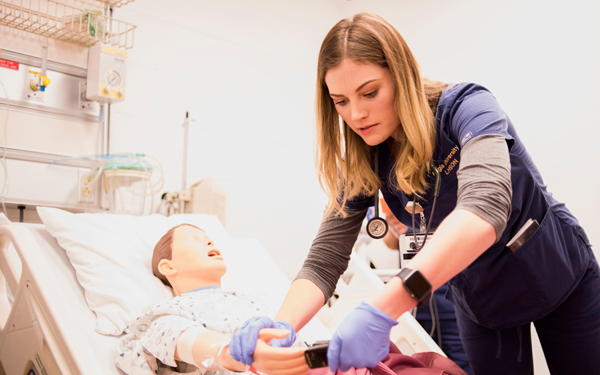Nursing student practicing clinical skills with a patient simulator in a healthcare training lab