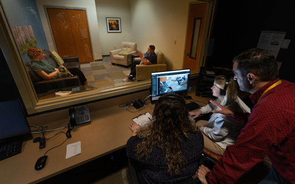 Students monitoring and evaluating a simulated counseling session from an observation room