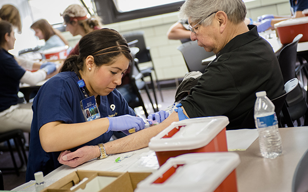 student drawing blood from a patient