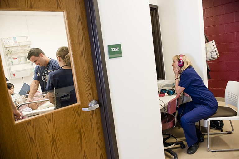 professor observing nursing students through window