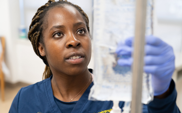Regis University nursing student adjusting an IV bag during clinical training