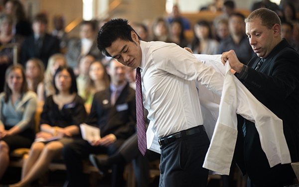 student receiving white coat at graduation
