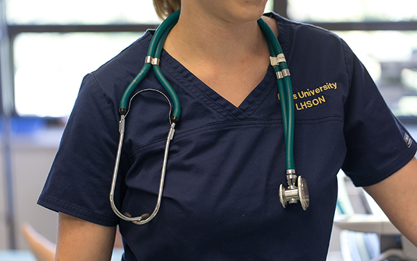 regis nursing student wearing scrubs and a stethoscope