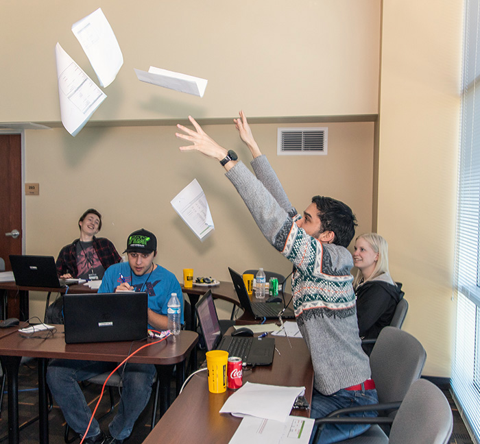 student throws papers in the air in computing classroom